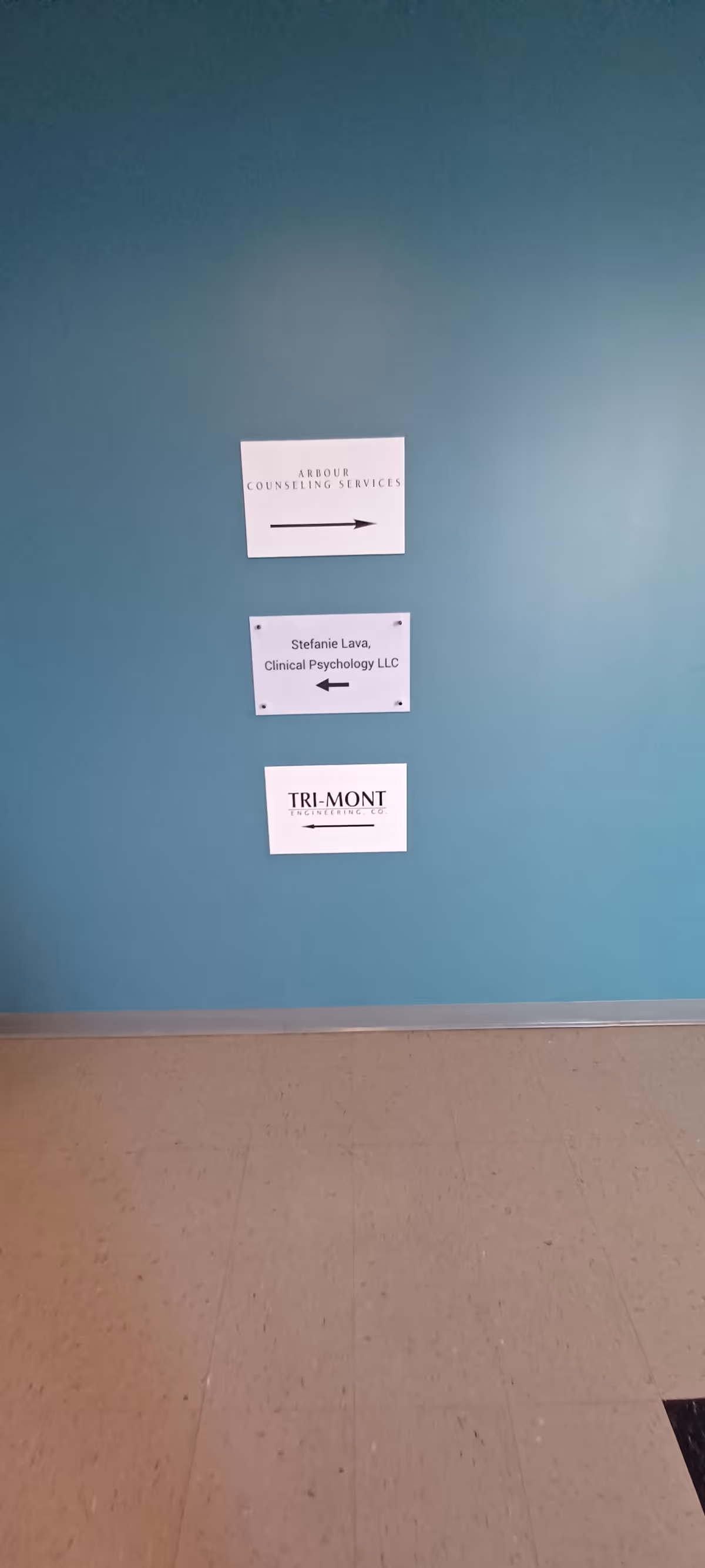 Teal hallway wall with three signs for Arbour Counseling Services.