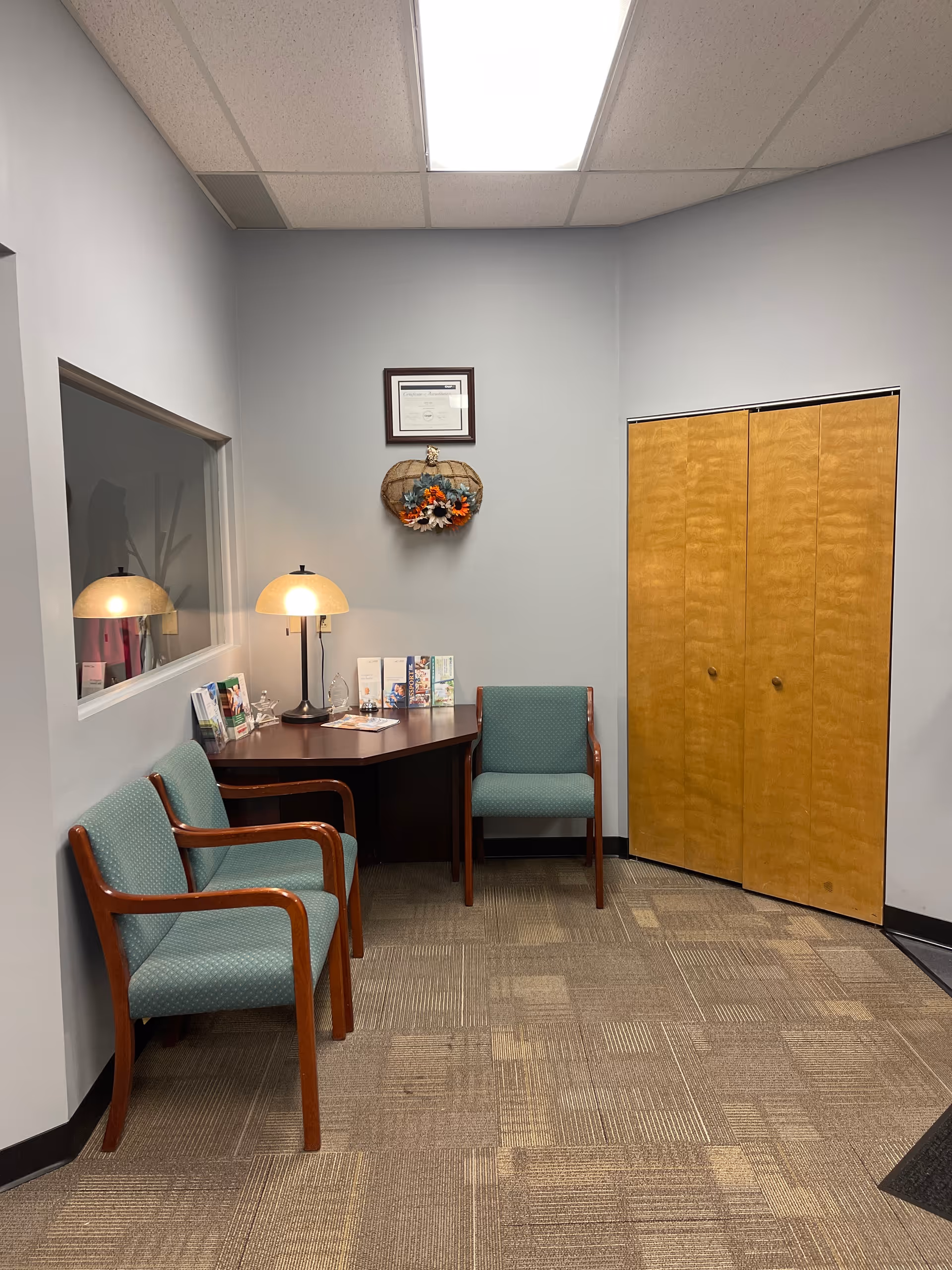 Interior waiting area in a LINCARE facility with two green chairs, a desk, and brochures.