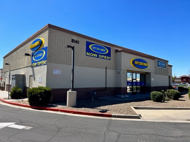 Exterior view of a MY DR NOW building with Now Open signs and parking area.
