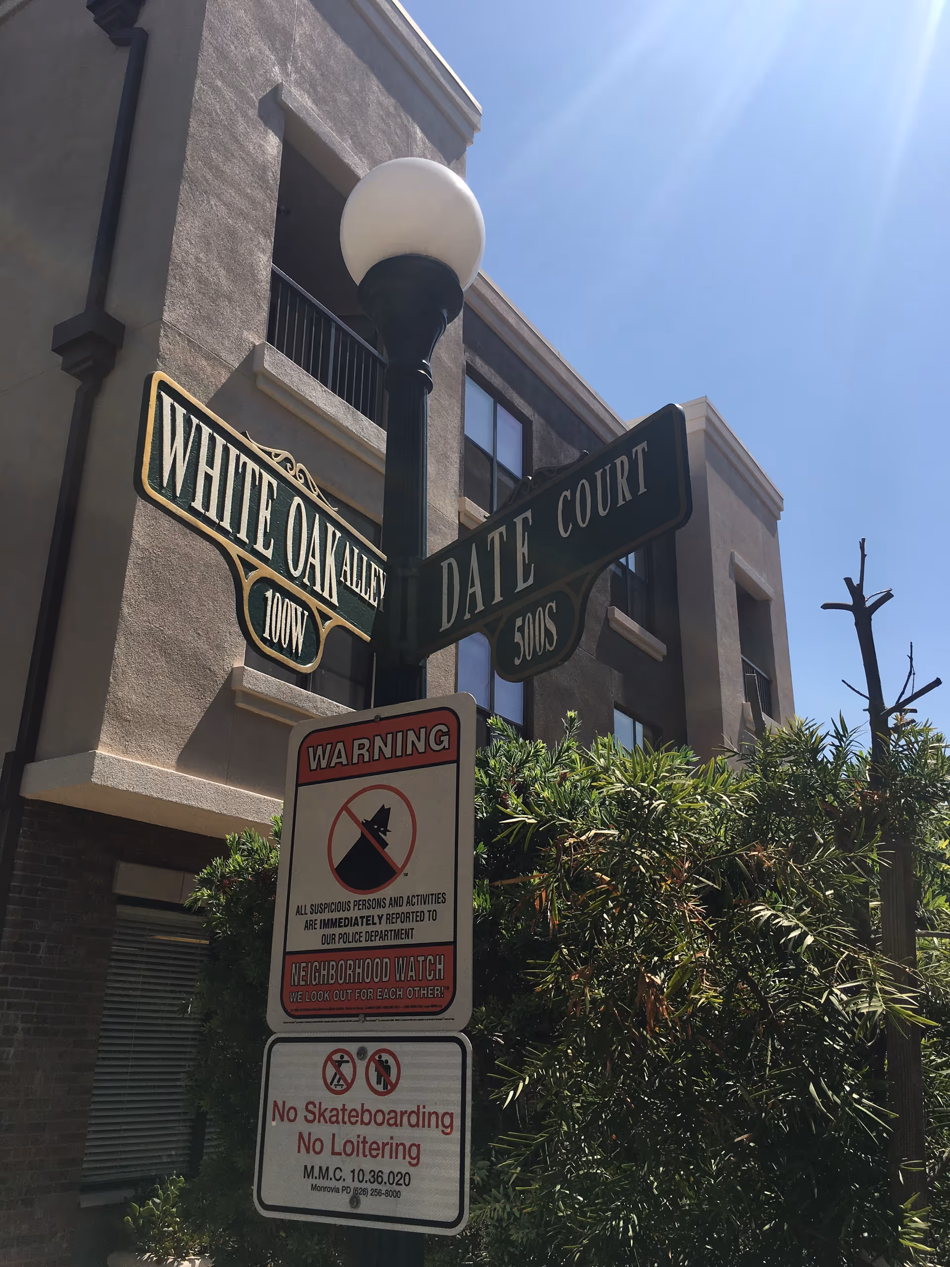 Exterior of a building with street signs White Oak Alley and Date Court beside shrubs