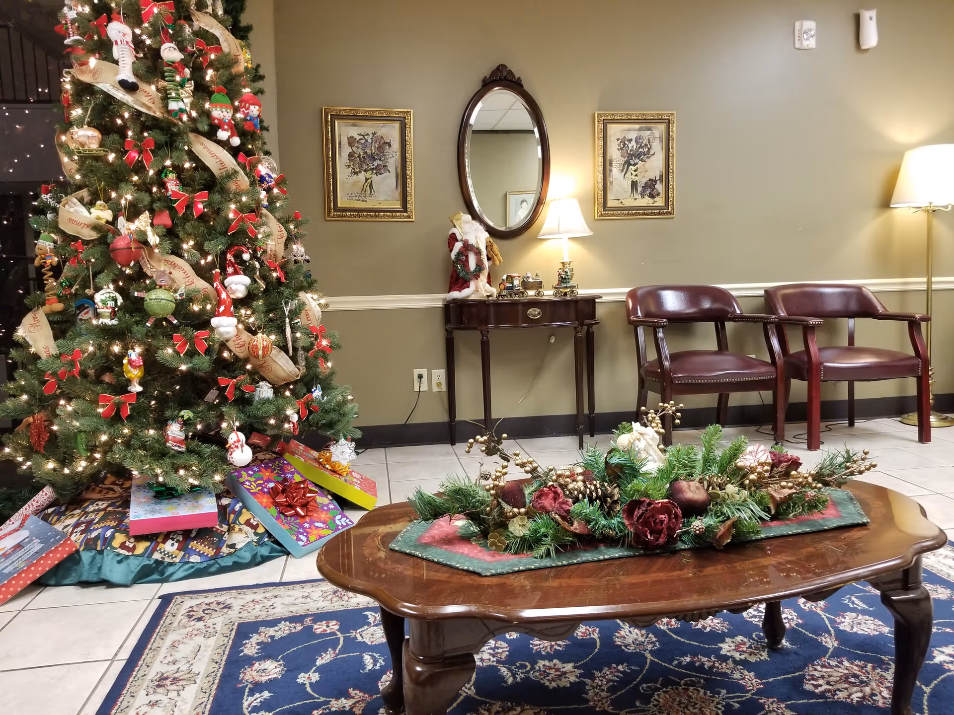 Holiday-decorated senior living lobby with Christmas tree, gifts, and seating area.