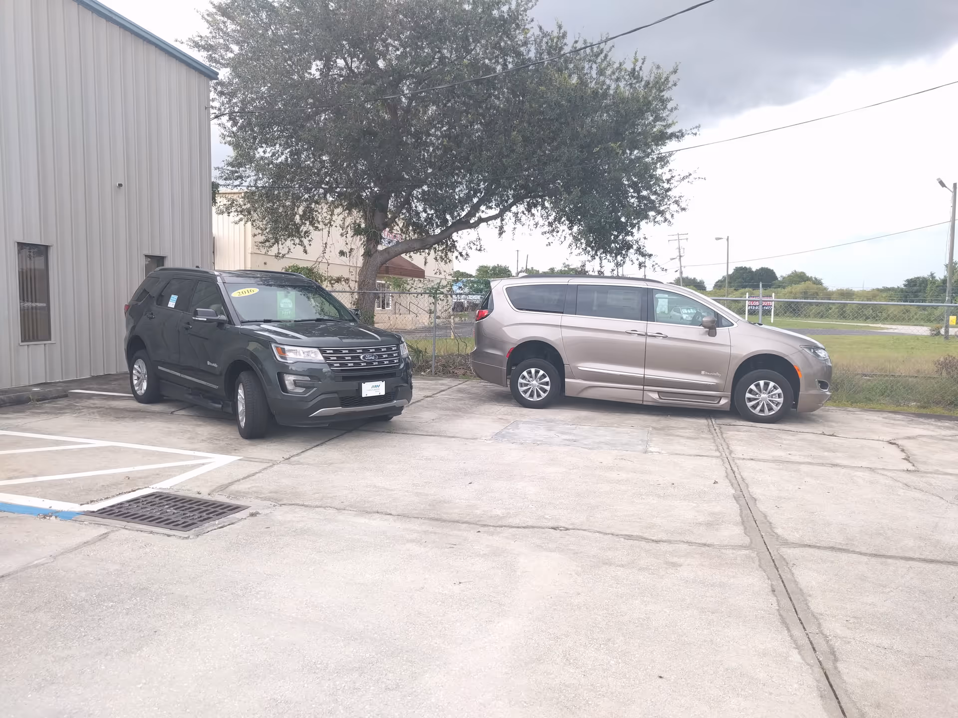 Two minivans parked in a lot beside a metal-sided facility building.