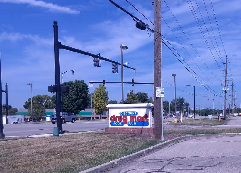 Wide street view with a Discount Drug Mart sign and traffic lights.