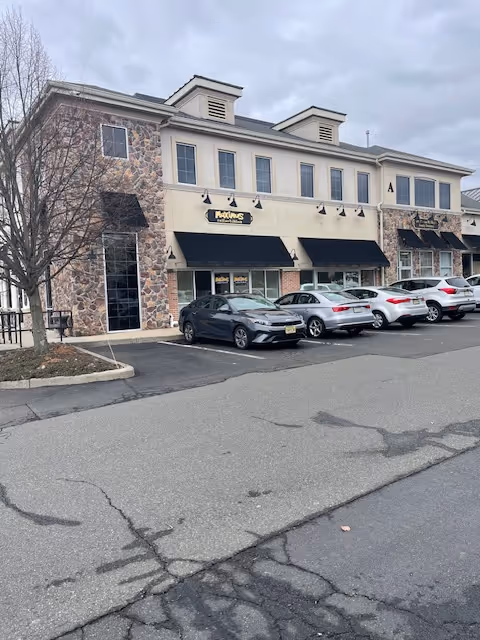 Exterior view of a strip-mall style building with stone accents and parked cars.