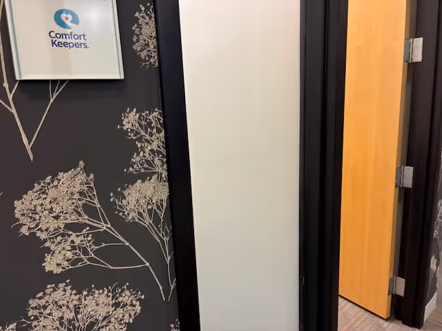 Interior hallway with floral wallpaper and a framed Comfort Keepers logo.
