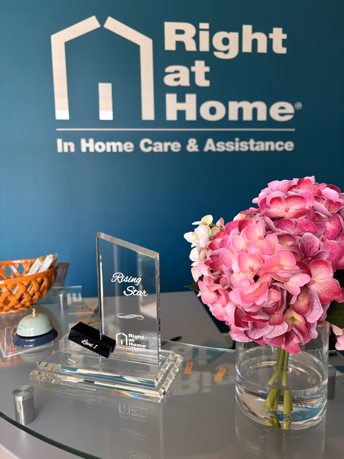 Reception desk area with a Right at Home sign, flowers, and an award plaque.