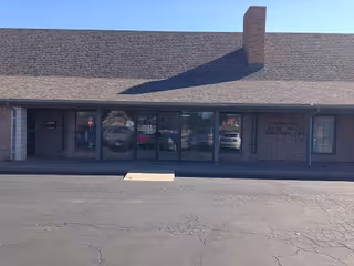 Front exterior of a single-story facility with glass entrance doors and brick facade.