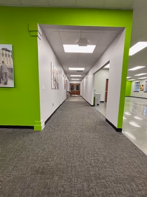 Interior hallway in a senior living facility with bright green walls and artwork.