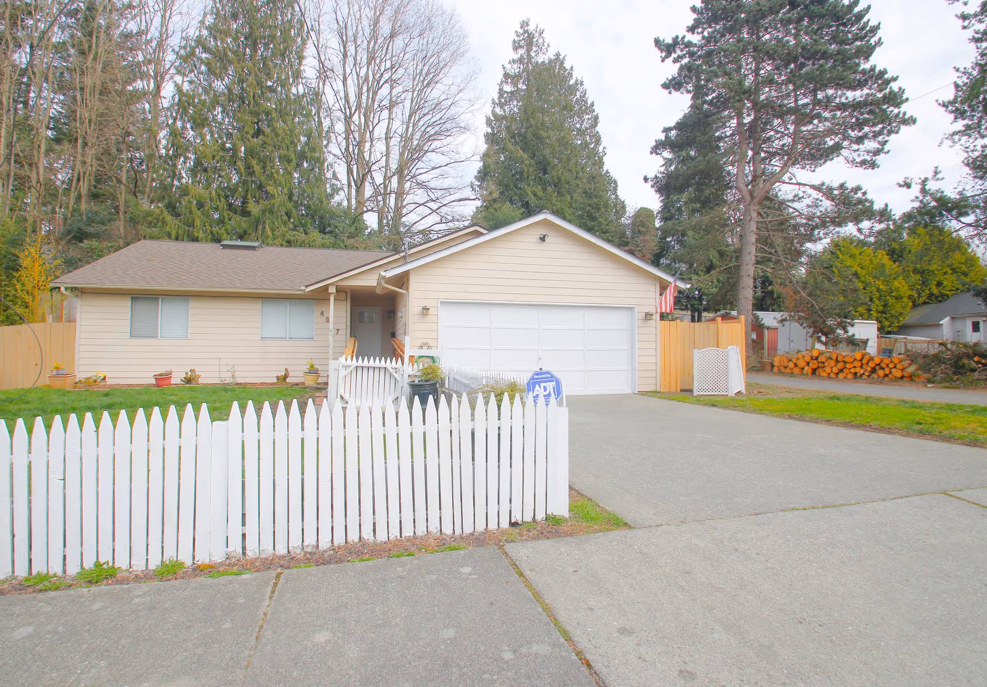Single-story beige home with white picket fence and a two-car garage.