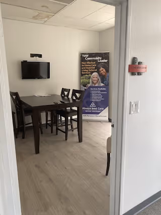 This small dining area features a table, chairs, a wall-mounted TV, and a banner.