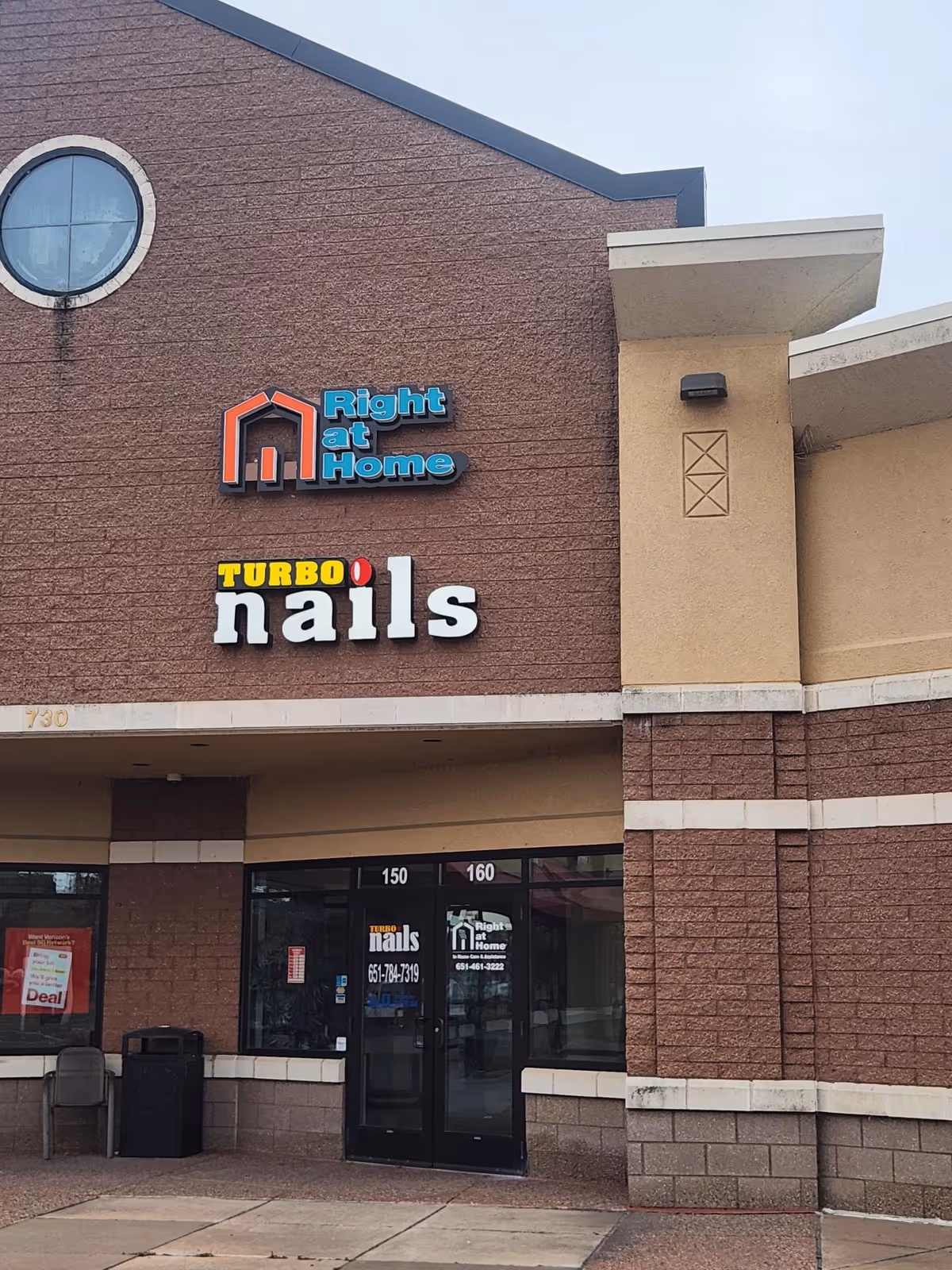 Brick storefront with Right at Home sign and Turbo Nails signage in a shopping plaza