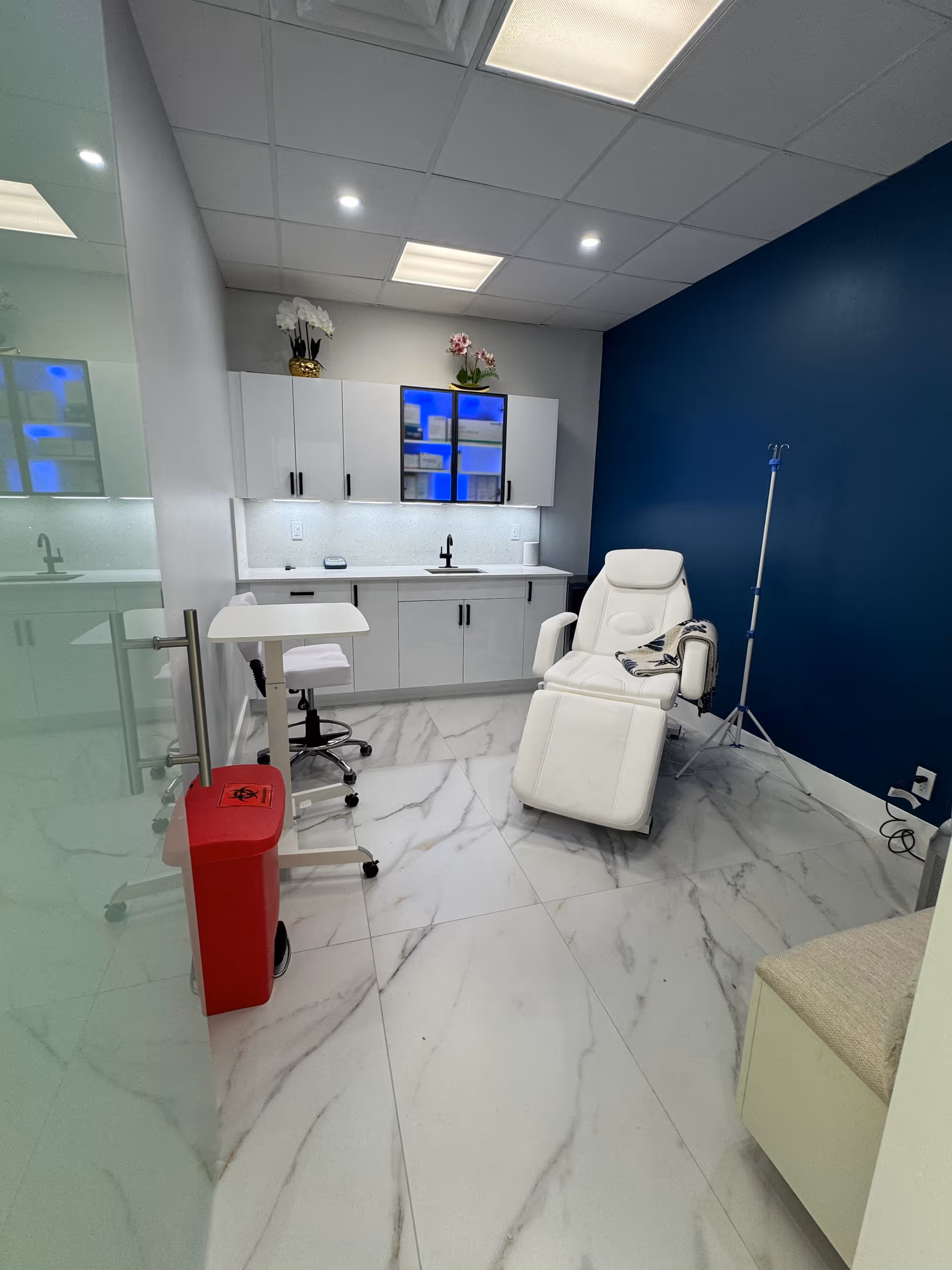 Treatment room with white cabinets, a reclining chair, and a blue wall.