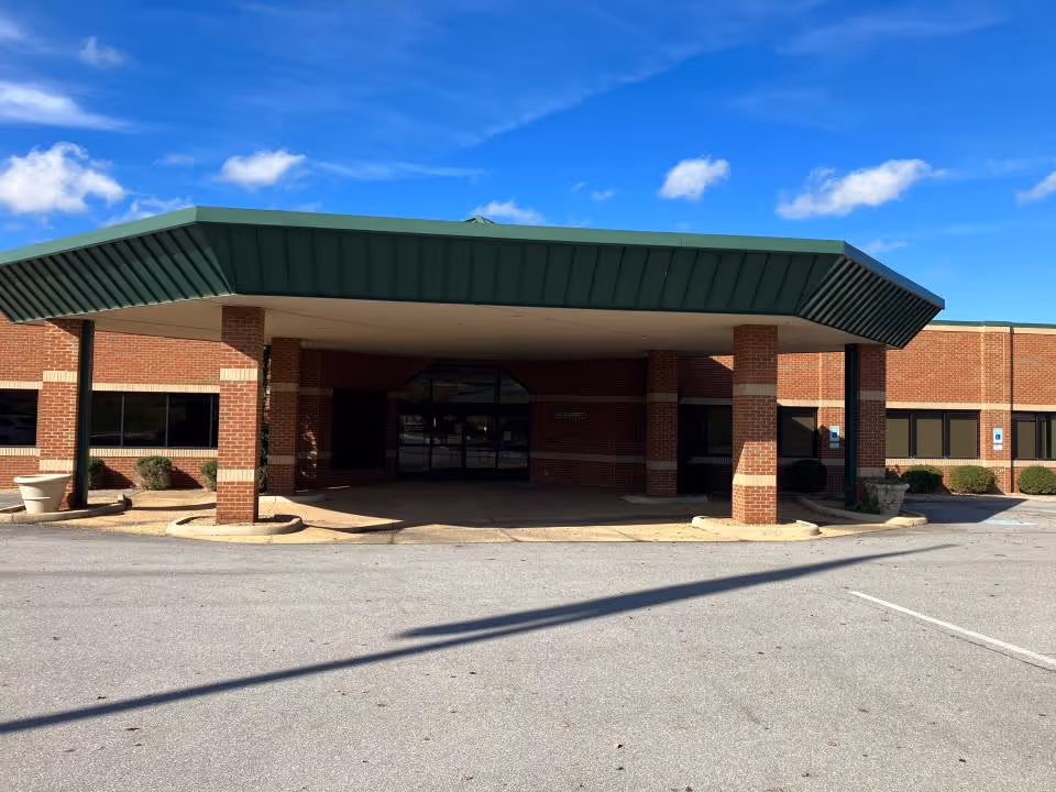Brick building entrance with a green canopy and brick columns.