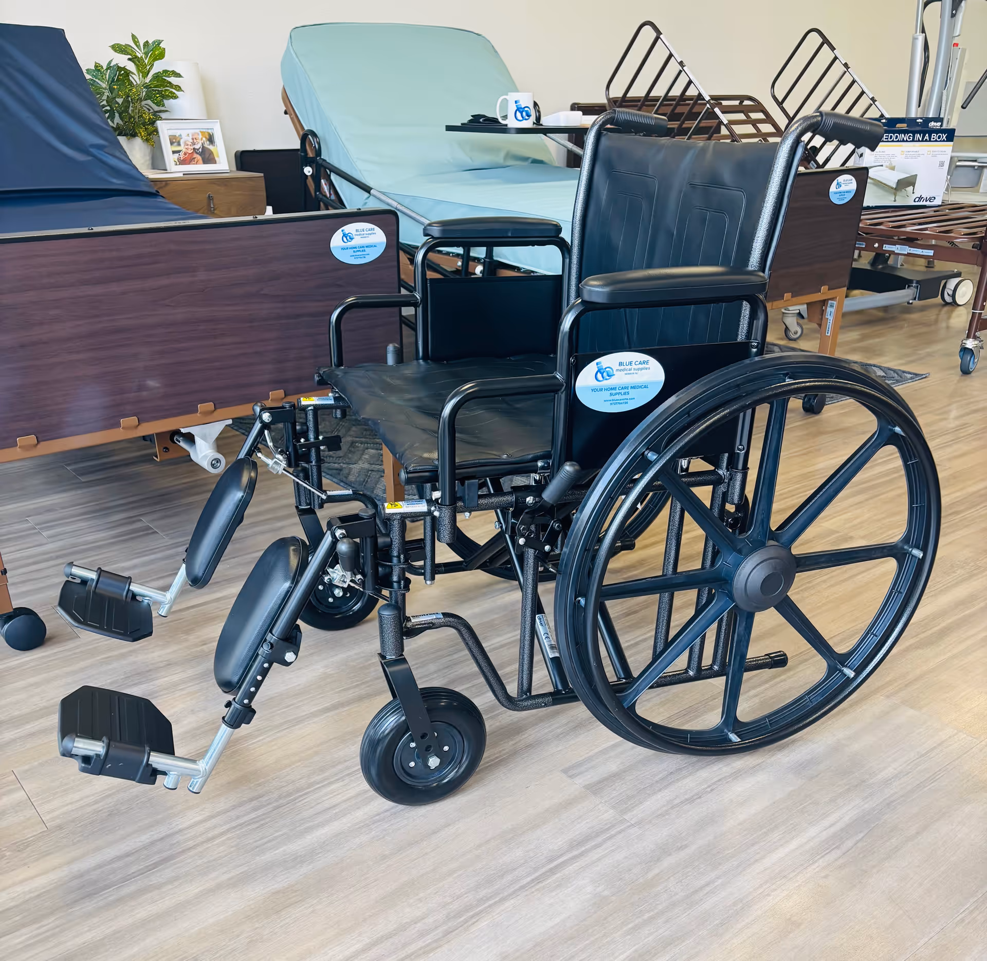 Black wheelchair in a senior living facility showroom with beds and medical equipment.
