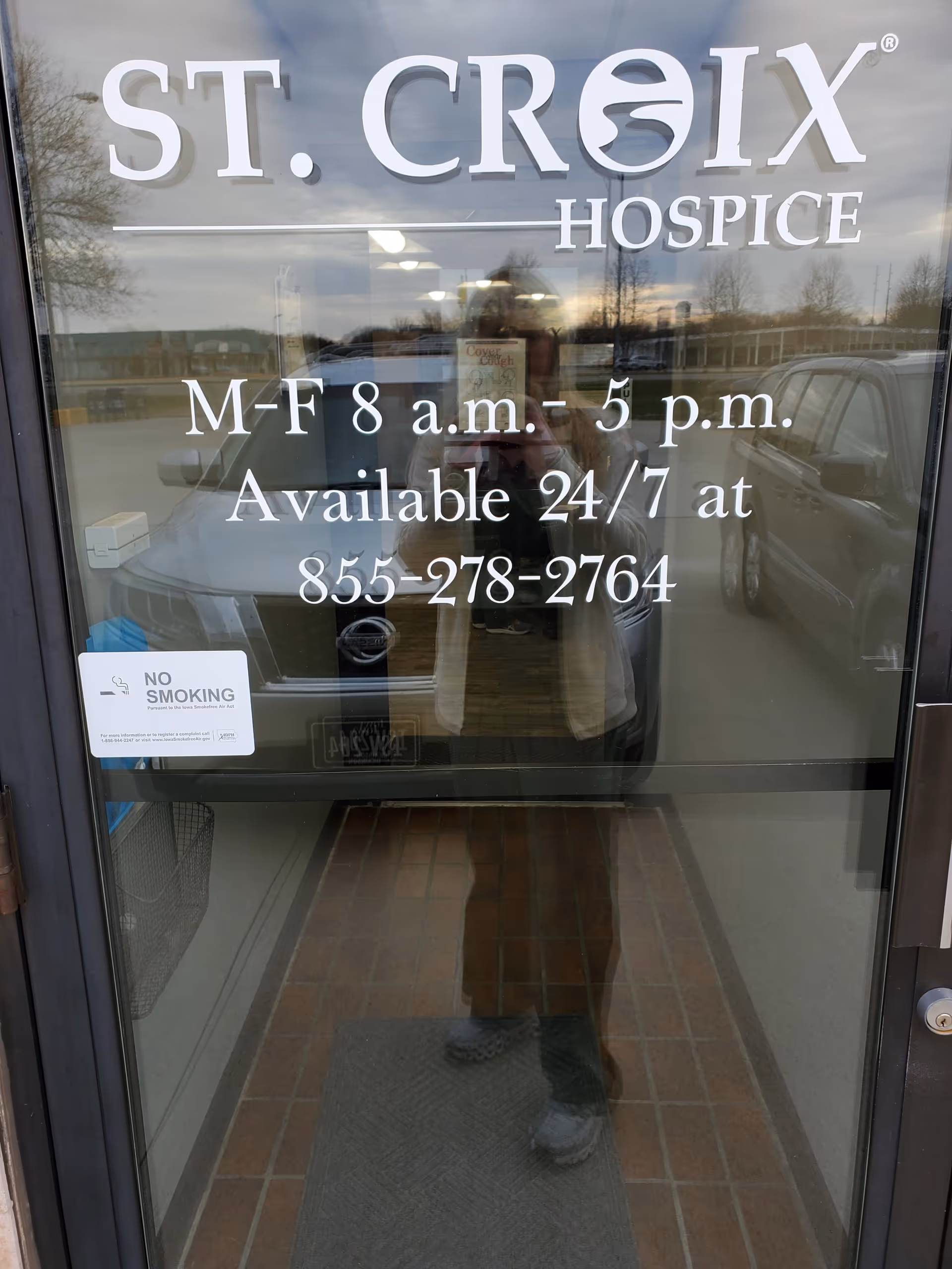 Glass front door of St. Croix Hospice displaying hours and contact information.