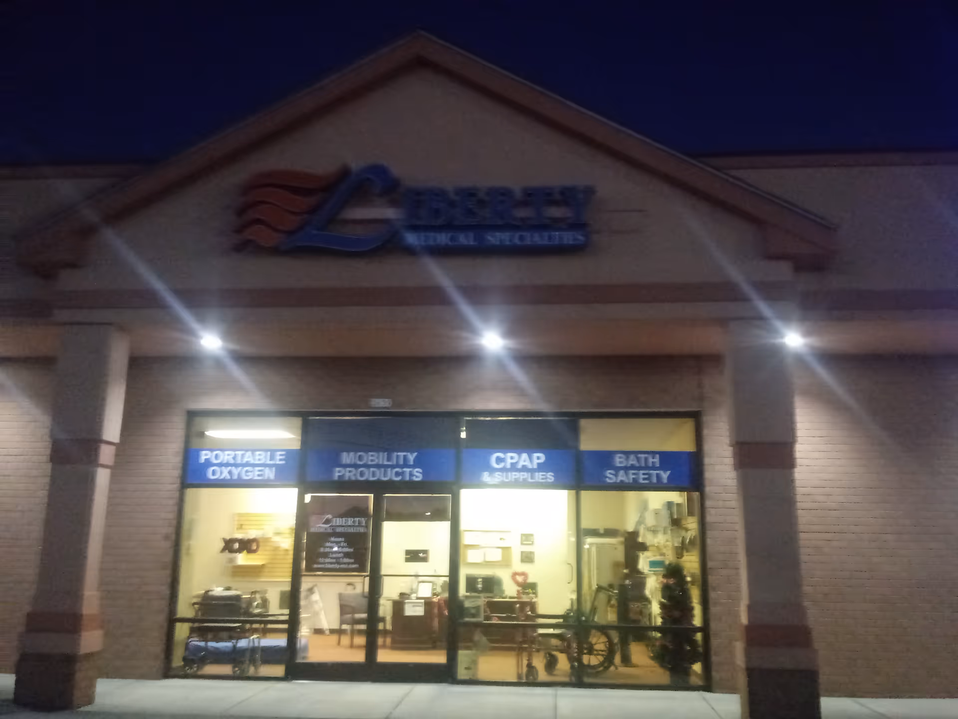 Night exterior of Liberty Medical Specialties storefront displaying blue signs for oxygen and CPAP products.
