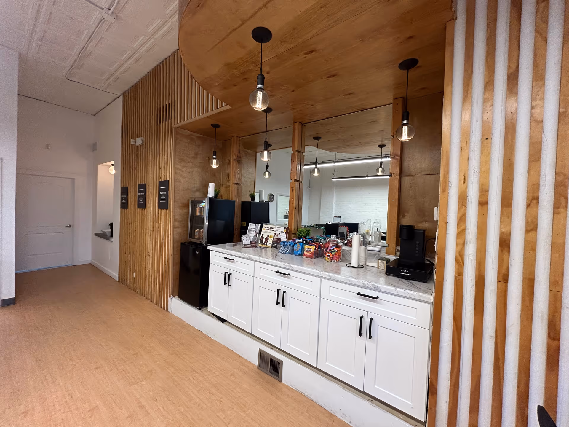 Modern service counter with white cabinets, wood panels, and pendant lights inside a senior facility.