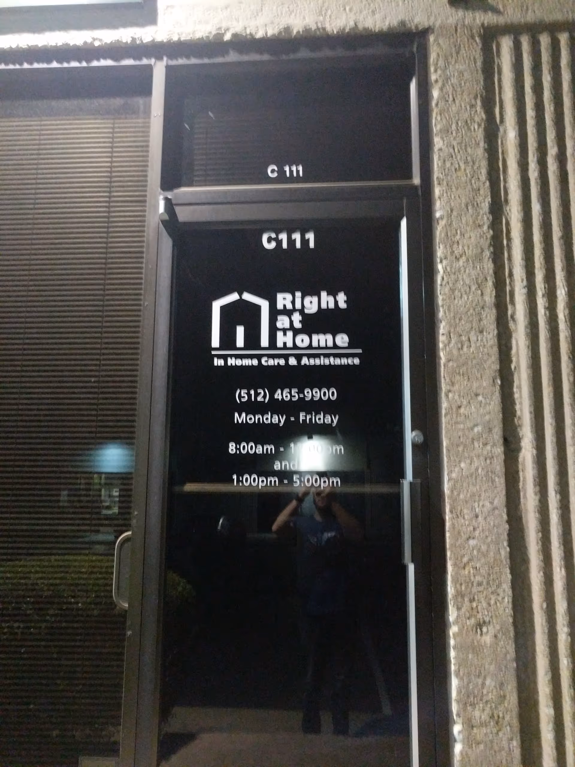 Glass door displaying Right at Home logo and hours, with photographer reflection.
