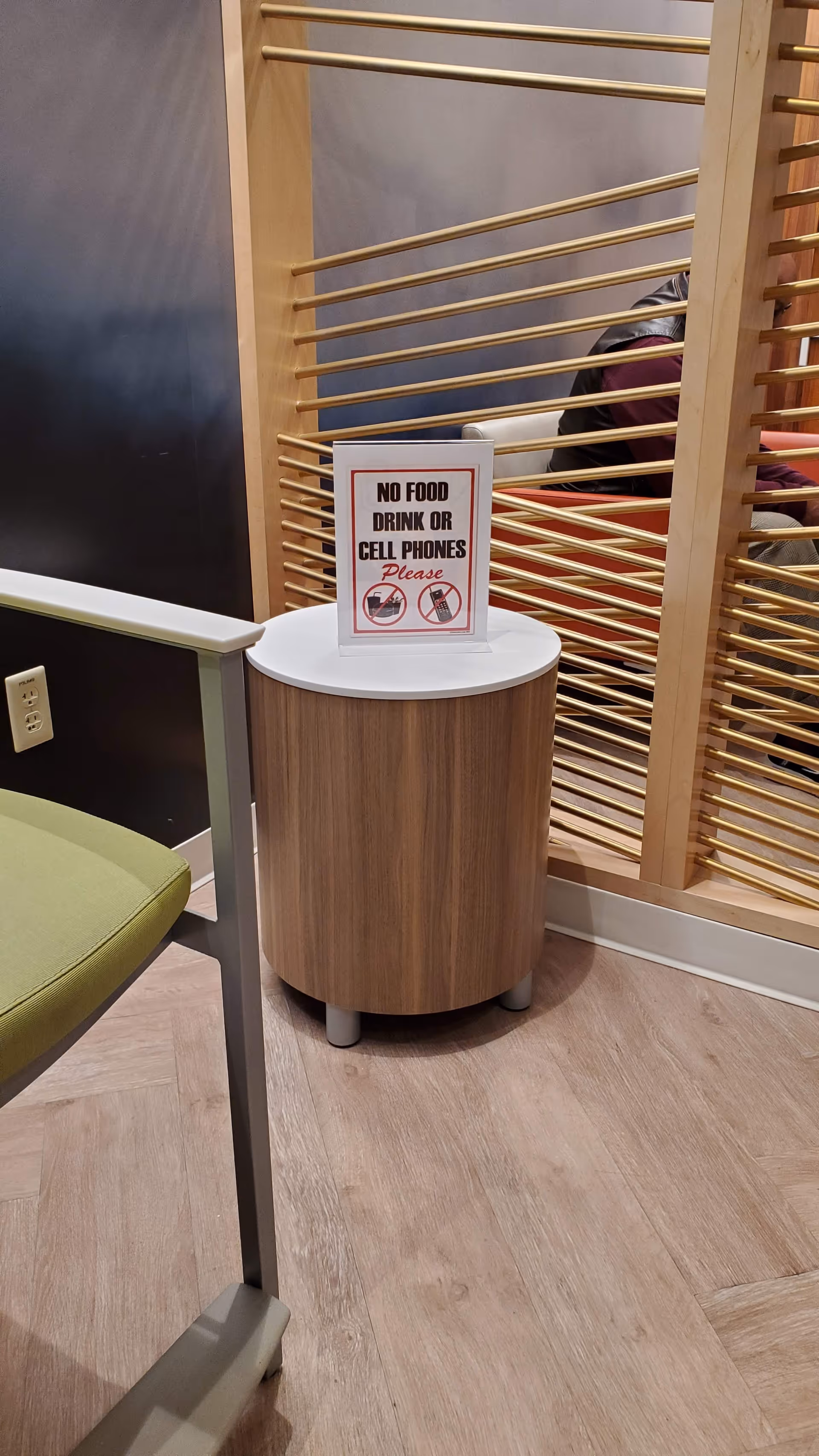 No food, drink, or cell phones sign on round wooden pedestal beside seating
