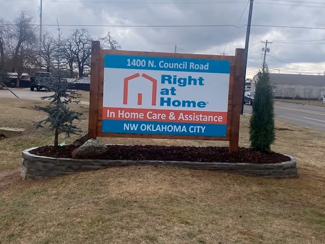 Outdoor sign for Right at Home in-home care, with landscaping and curved stone border.