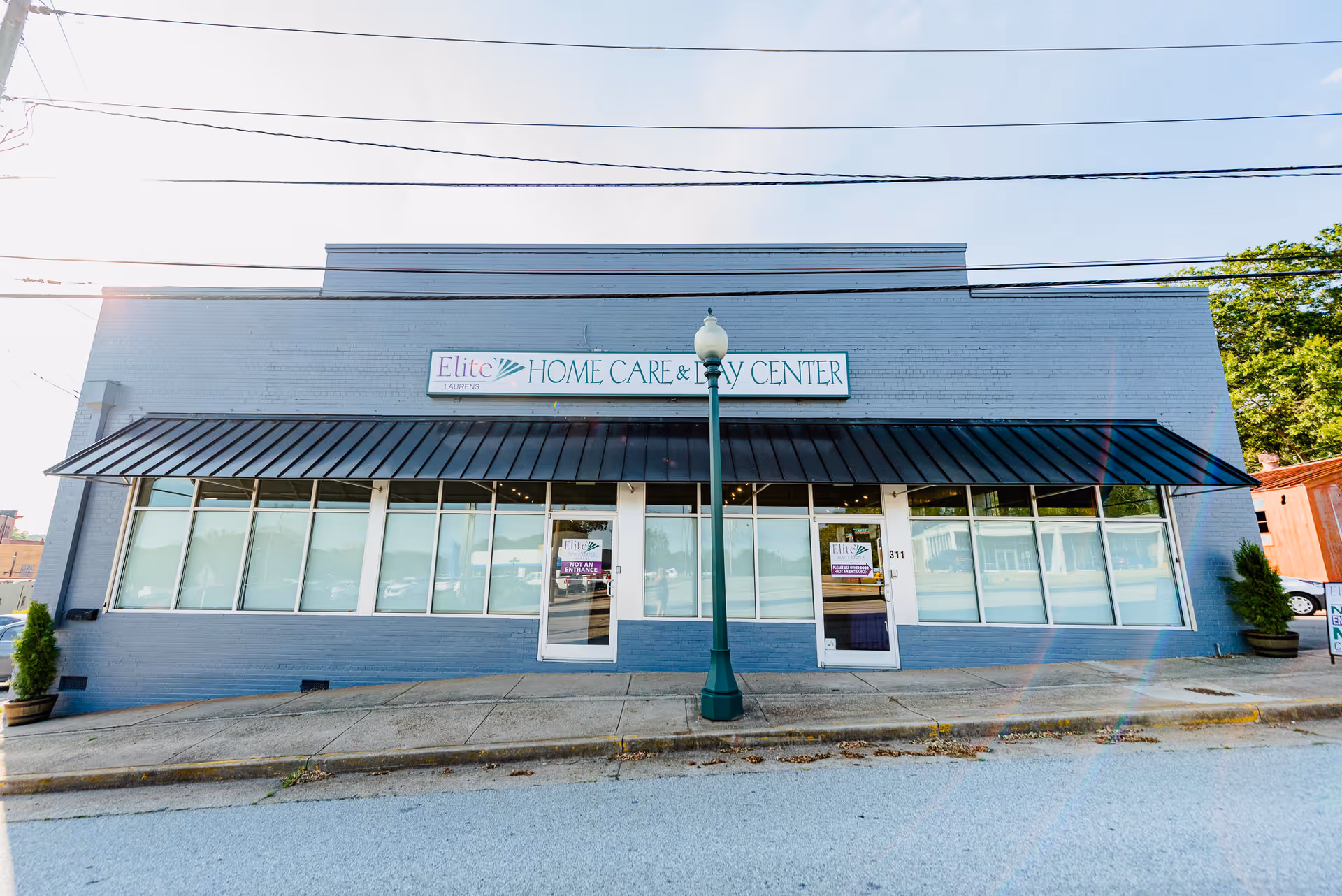 Blue-gray storefront building with large windows and a sign reading Elite Home Care and Day Center.