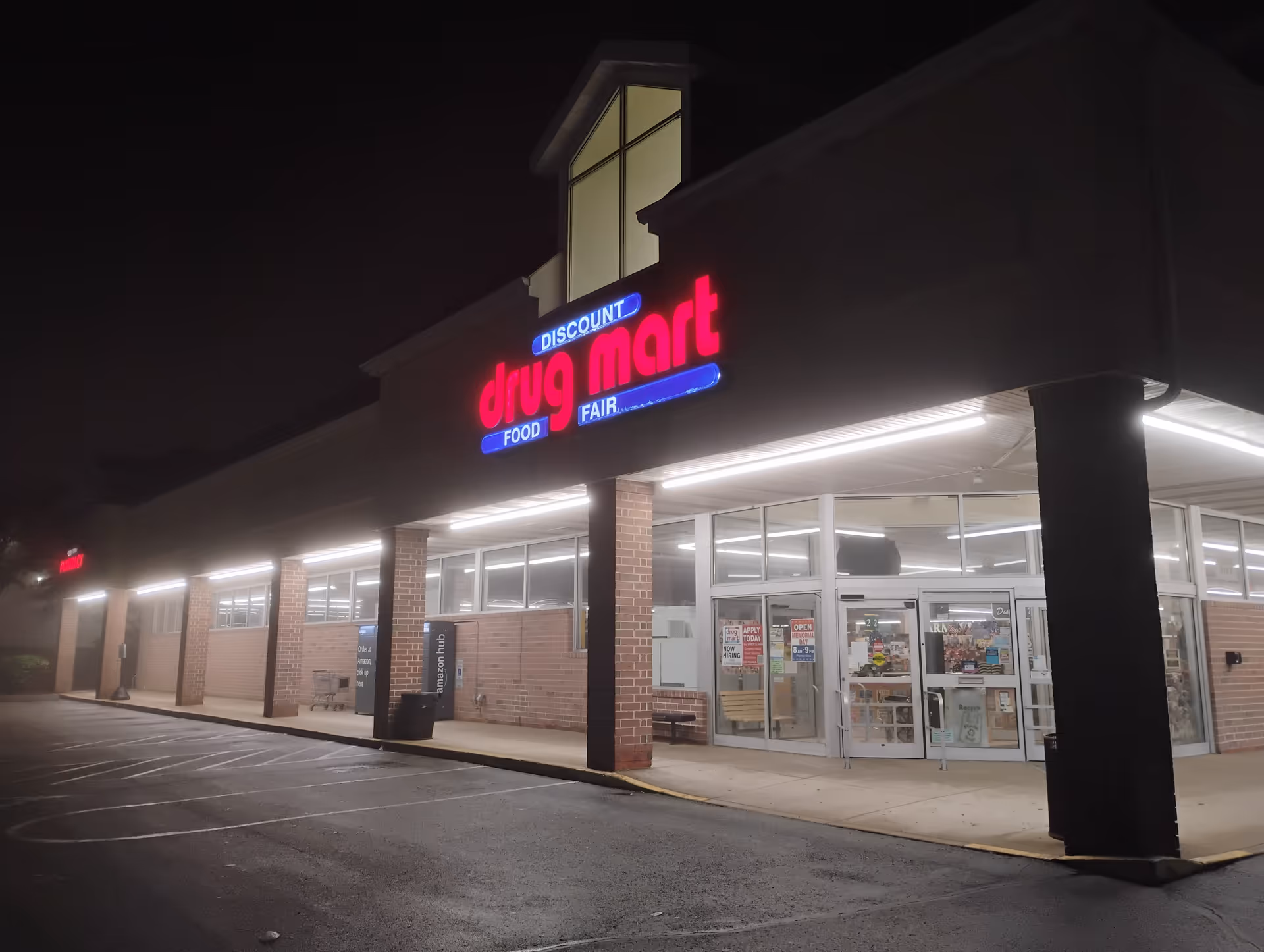 Nighttime exterior of Discount Drug Mart with an illuminated sign and glass entrance.