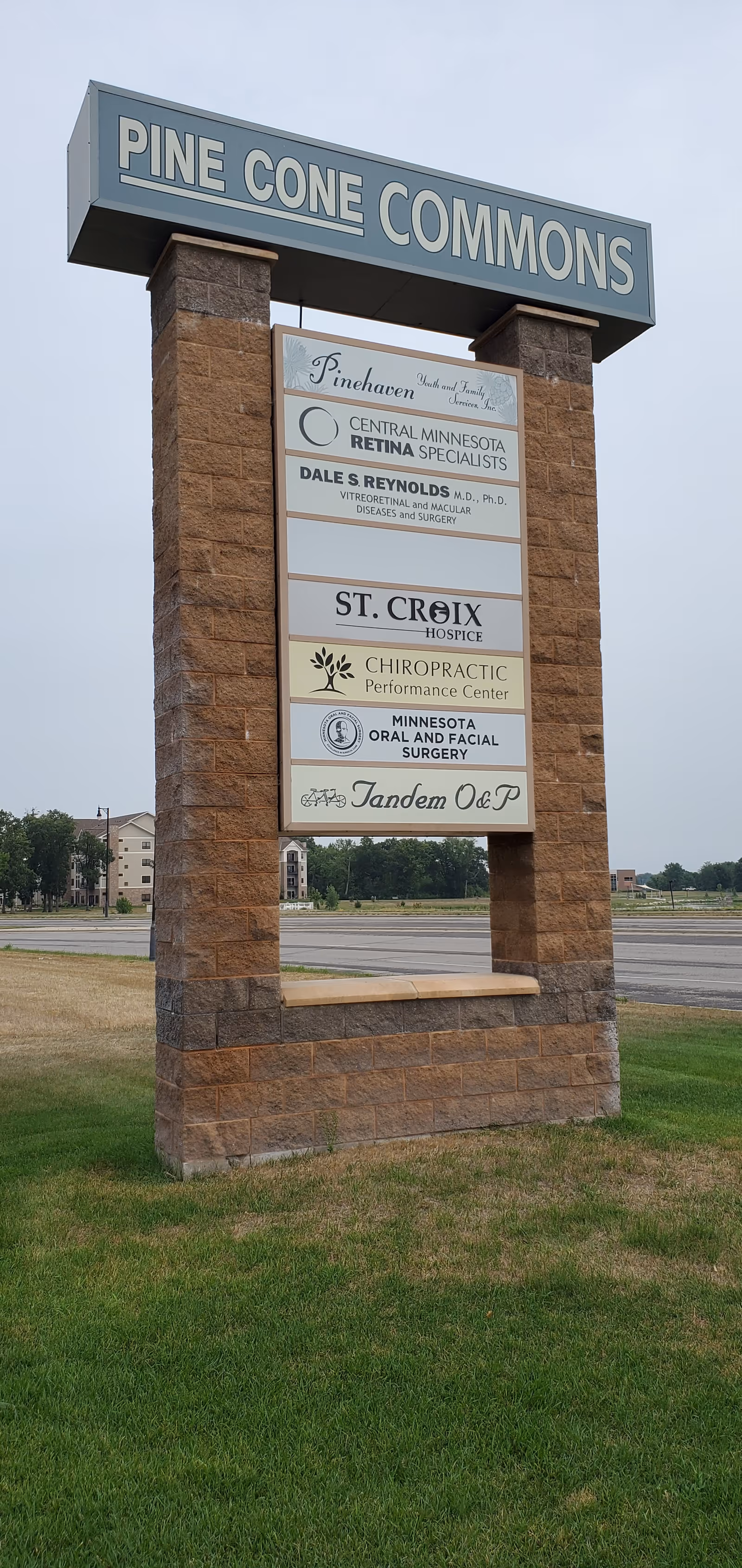Outdoor stone sign displaying Pine Cone Commons and tenant listings including St. Croix Hospice.