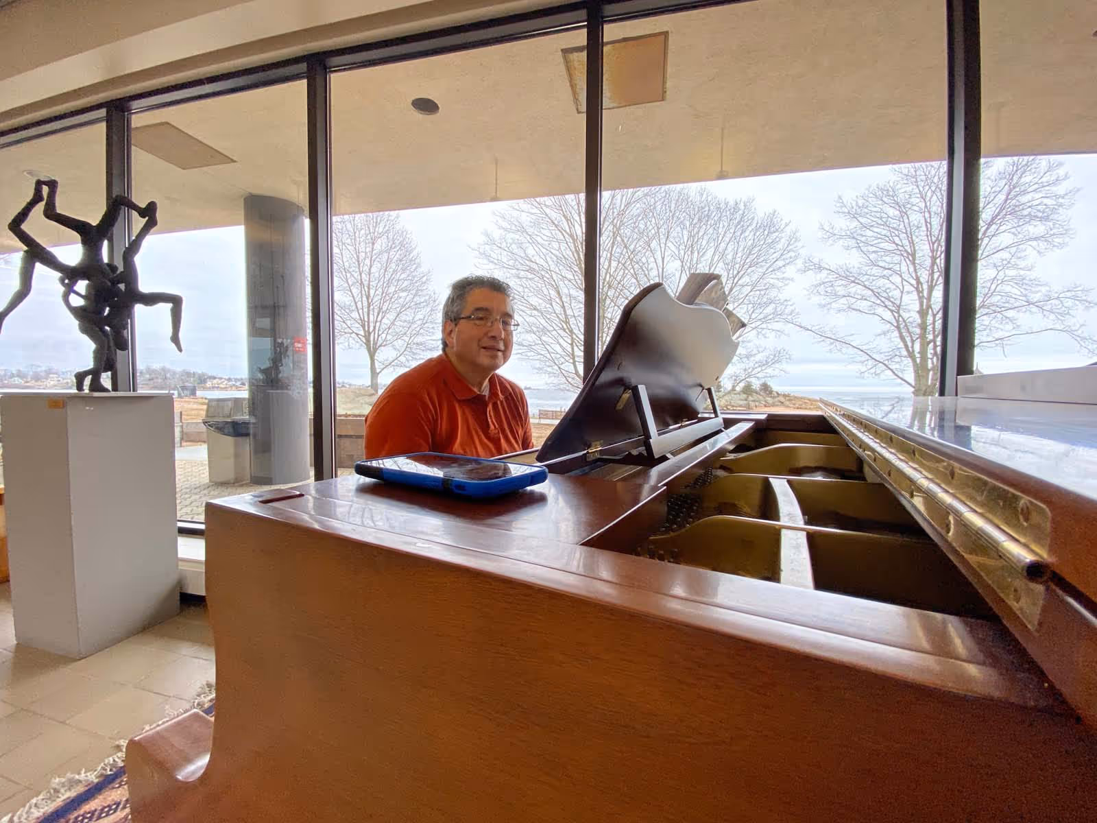 A man sits at a grand piano inside Connecticut Hospice's bright lounge.