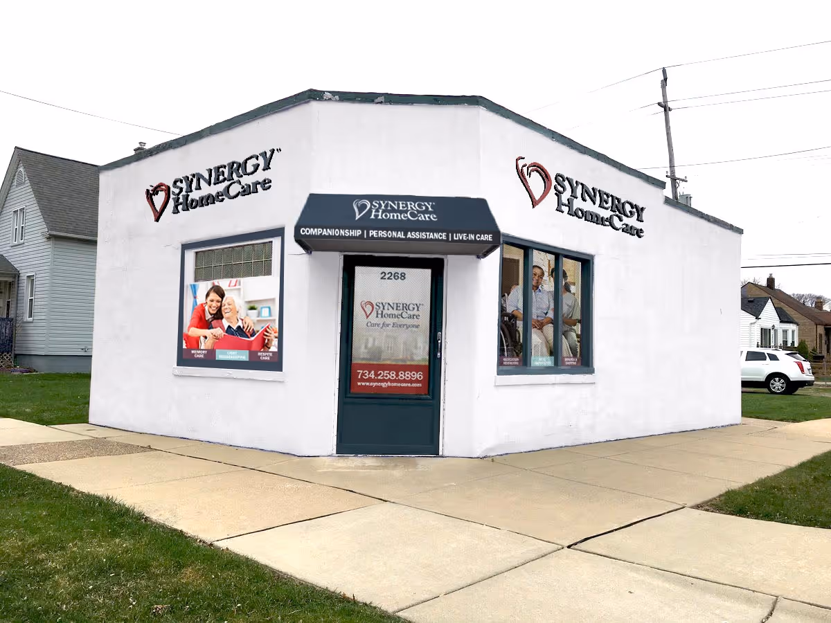 White SYNERGY HomeCare building with a dark awning and large storefront windows.