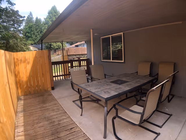 Outdoor covered patio with a glass-topped table and six chairs.