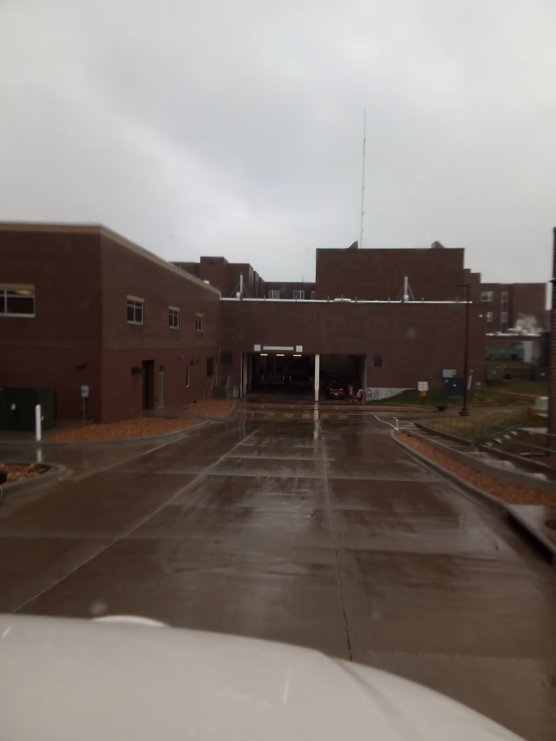 Brick healthcare building with a covered entrance and wet concrete driveway.
