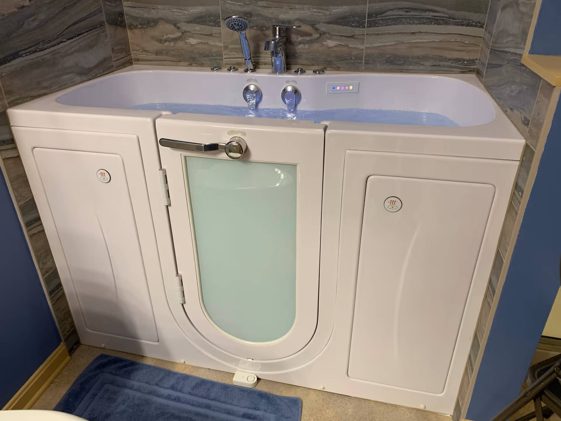 Accessible walk-in tub with door and frosted panel in a tiled bathroom.