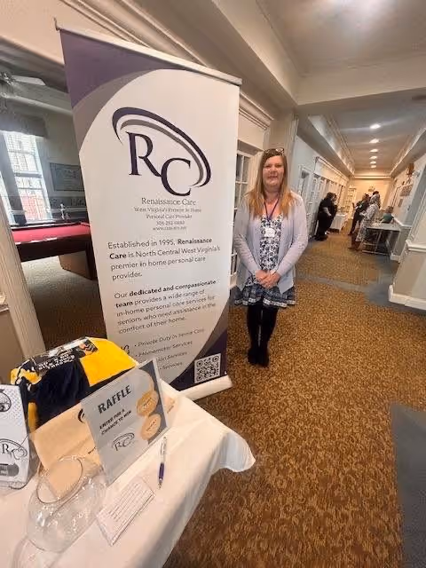 Woman stands in a hallway beside a Renaissance Care banner and raffle table.