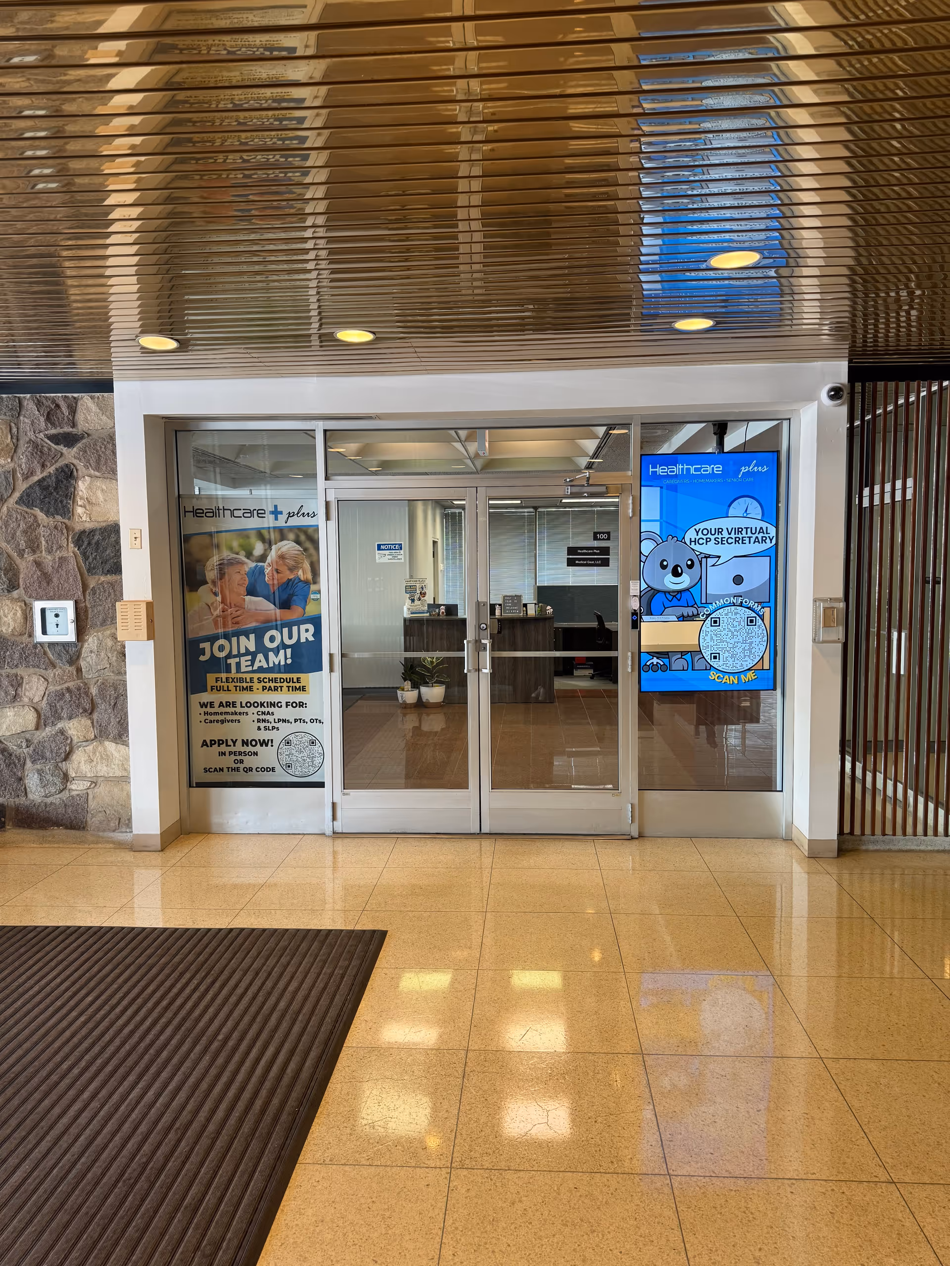 Indoor facility lobby with glass doors, a reception desk, and posters.