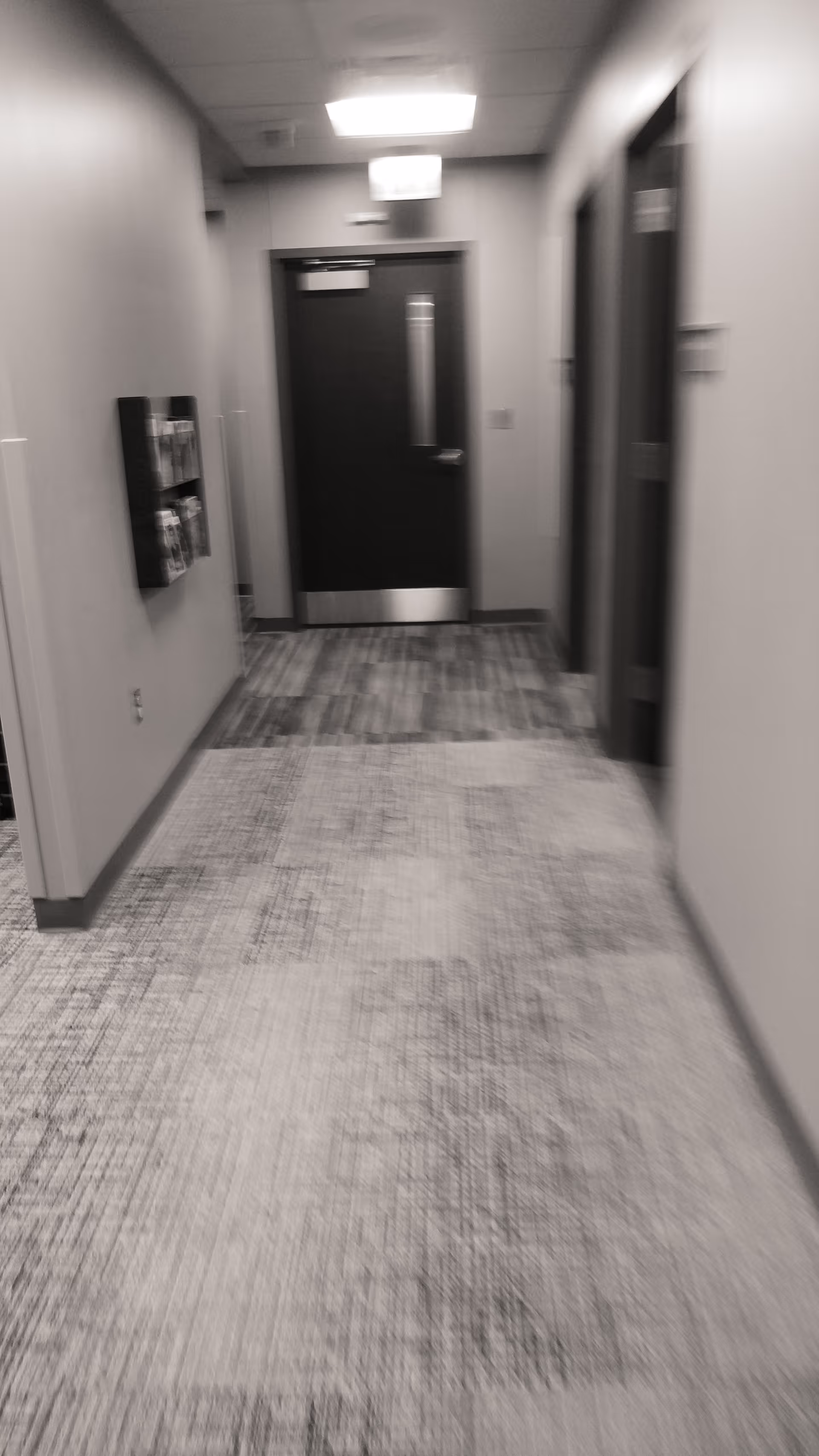 Gray hallway in a senior living facility with closed doors and ceiling lights.