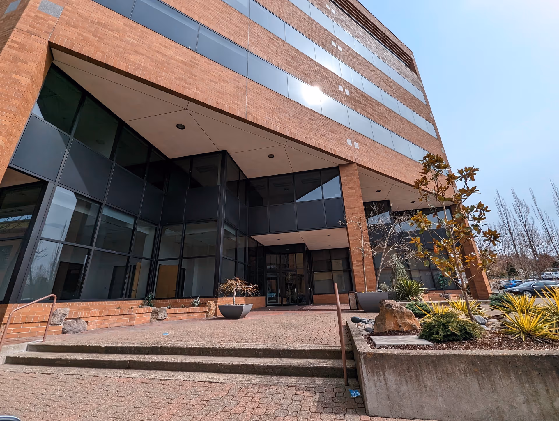 Brick, multi-story building with glass entrance and landscaped front walkway.