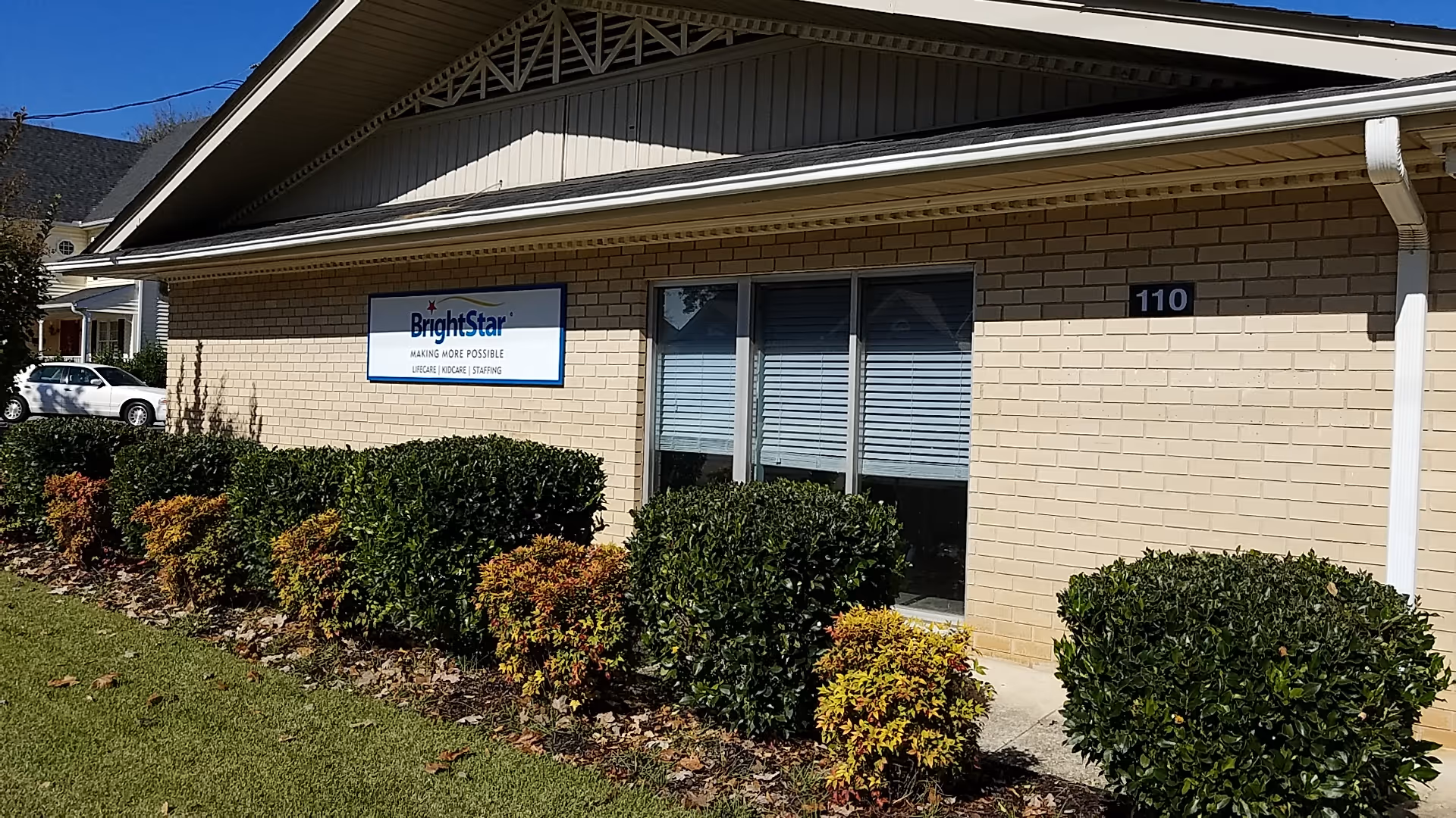 Exterior view of BrightStar senior care building with shrubs and sign.