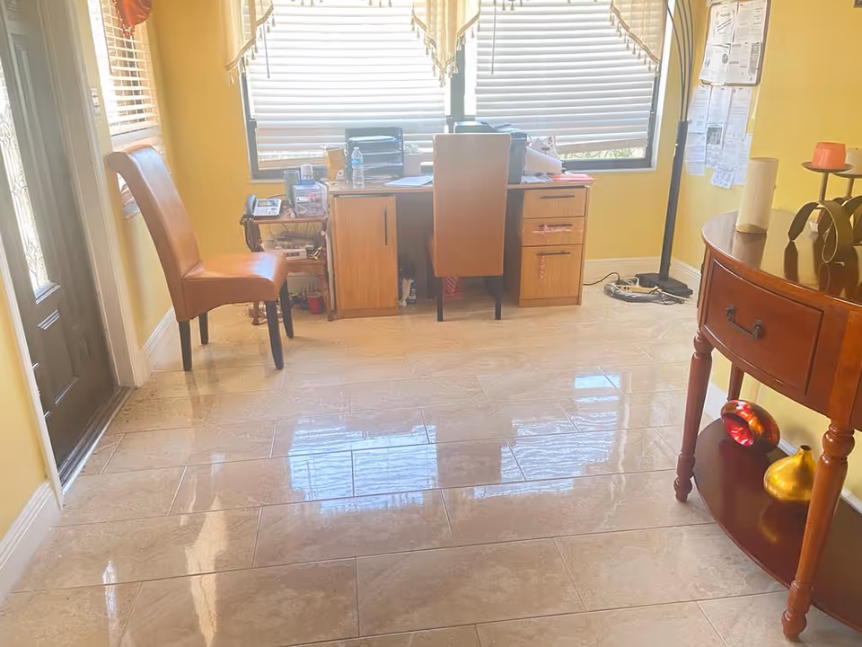 Interior room in care home with yellow walls, desk, chair by windows, and curved console table.