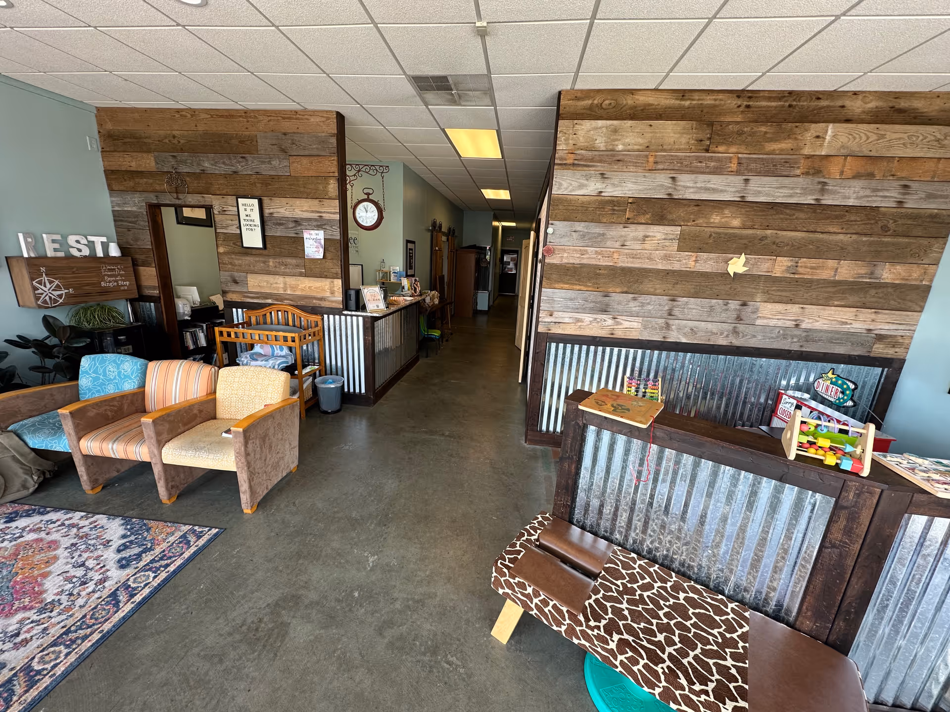 Cozy lobby area with mixed seating, rustic wood walls, and a reception desk.