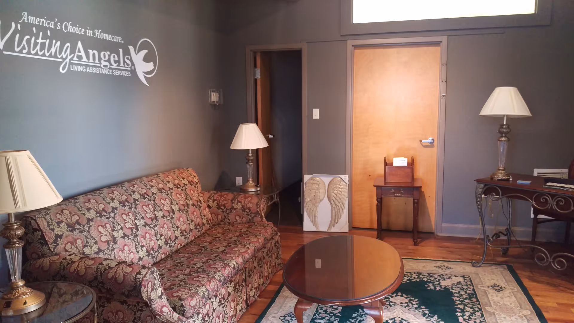 A cozy waiting area in a Visiting Angels senior home care facility, with couch and lamps.