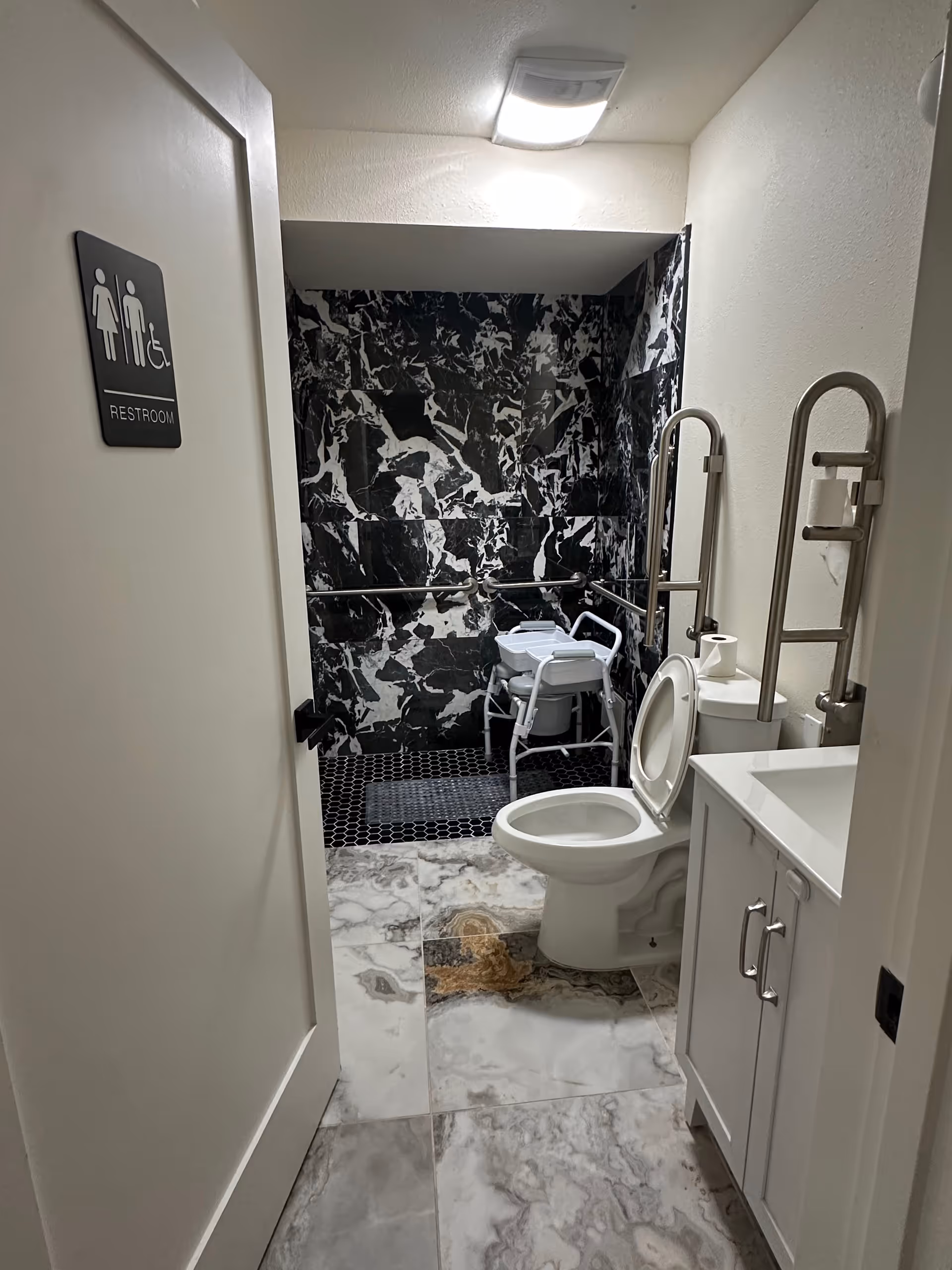 Accessible bathroom with a walk-in shower, grab bars, toilet, and sink.