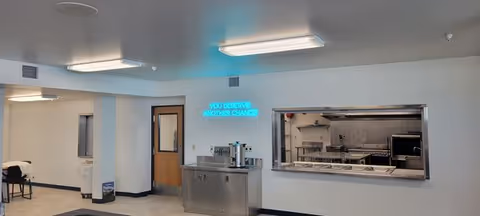 Sterile facility kitchen area with pass-through window, beverage station, and neon sign.