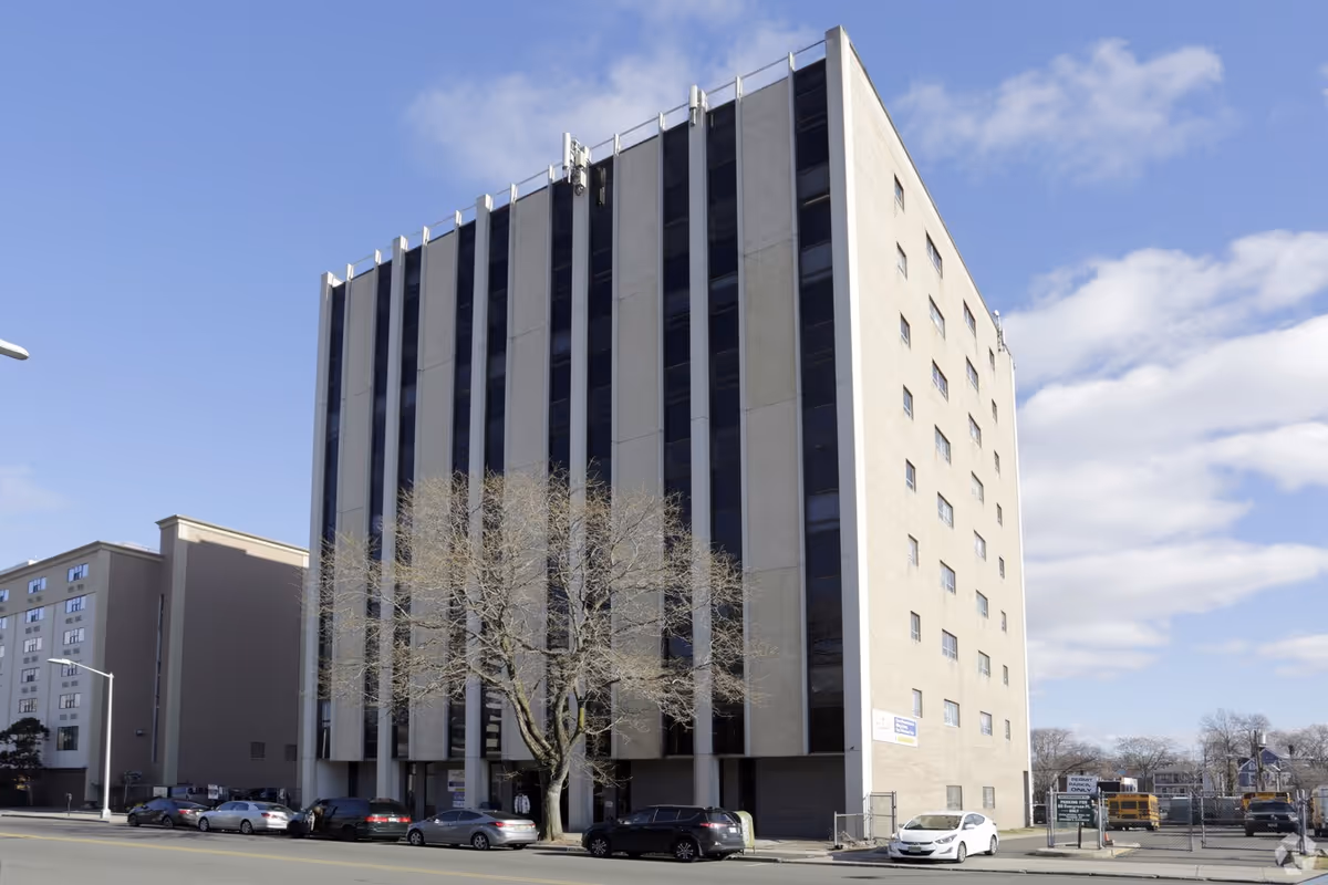 Exterior view of a tall, modern multi-story care facility along a city street.