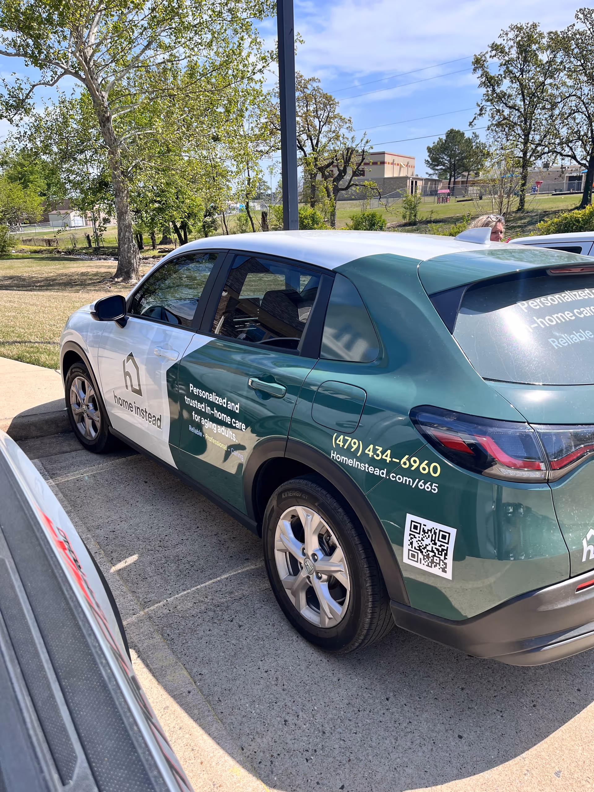 Green Home Instead branded vehicle in a parking lot with trees
