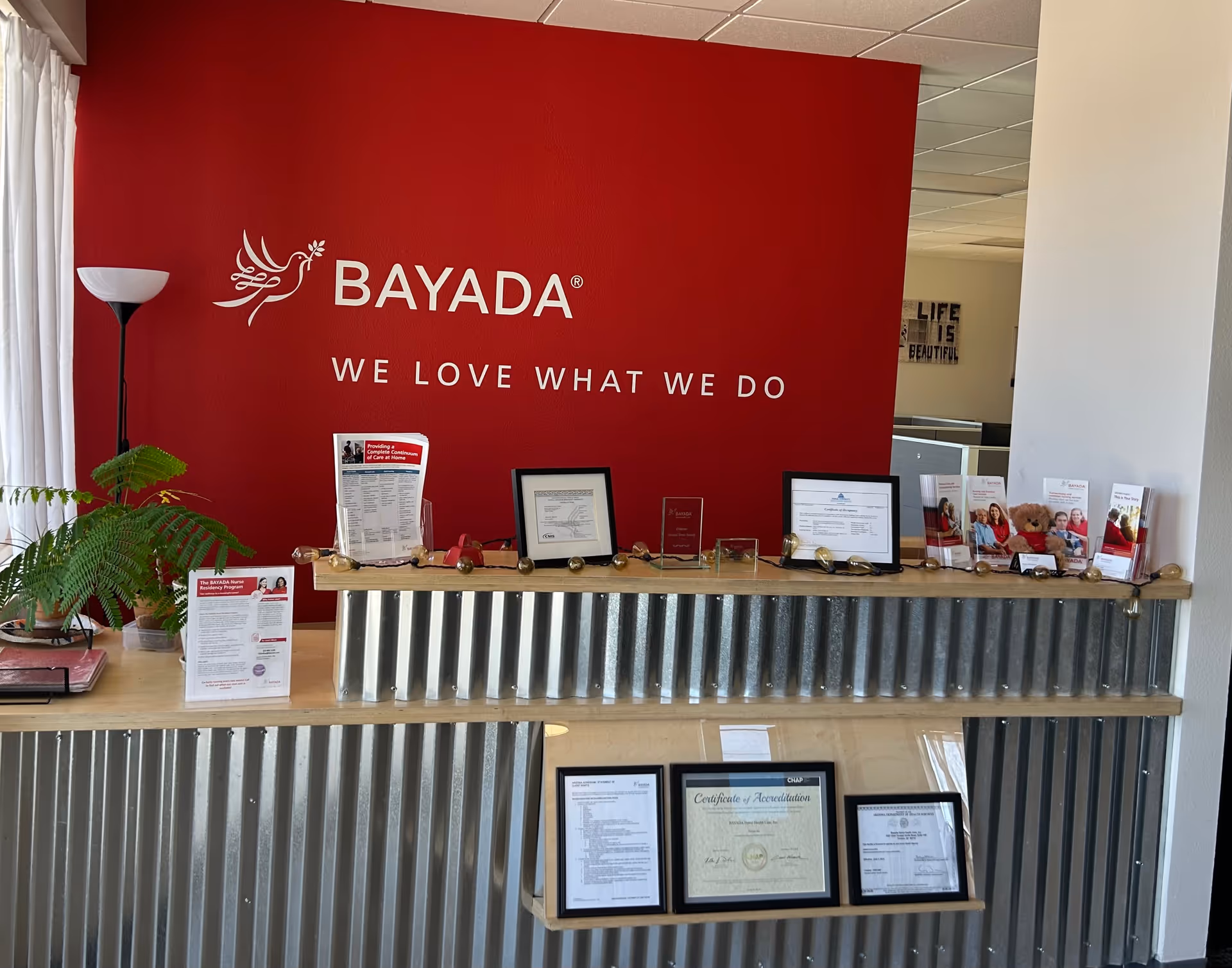 Reception desk in BAYADA facility with a red wall, certificates, and brochures.