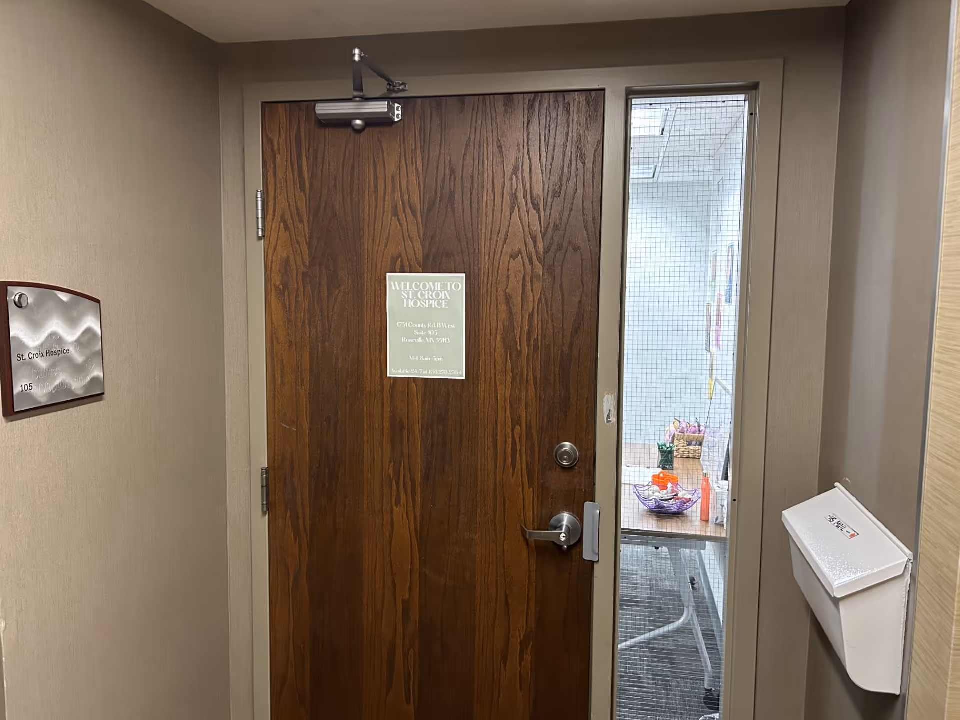 Wooden door in a hallway with a St. Croix Hospice plaque.