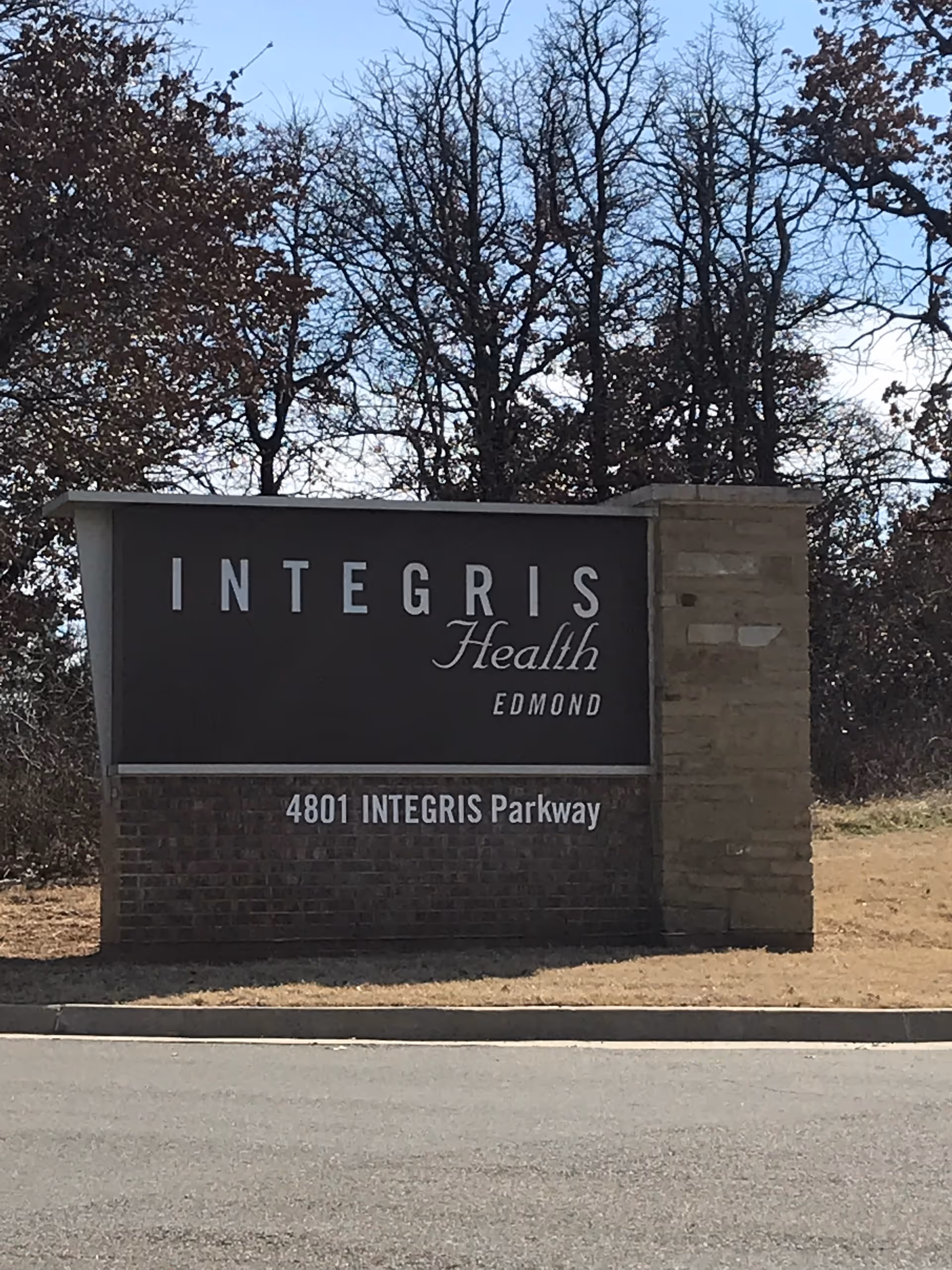 Exterior view of a stone sign for Integris Health Edmond with trees in the background