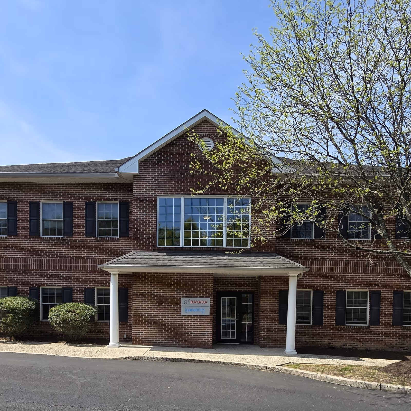 Brick two-story Bayada Assistive Care facility with a covered entrance and a tree.