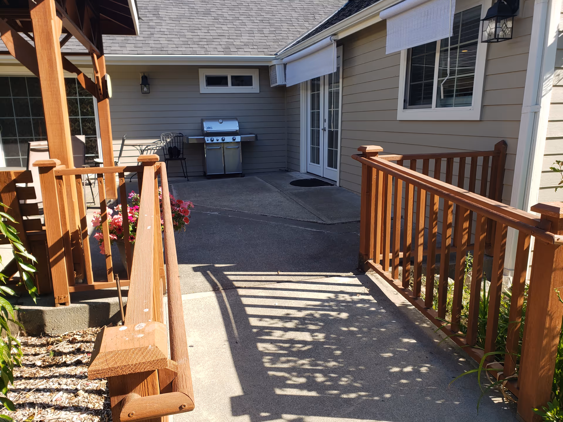 Outdoor patio area with wooden railings, a barbecue grill, and exterior doors.