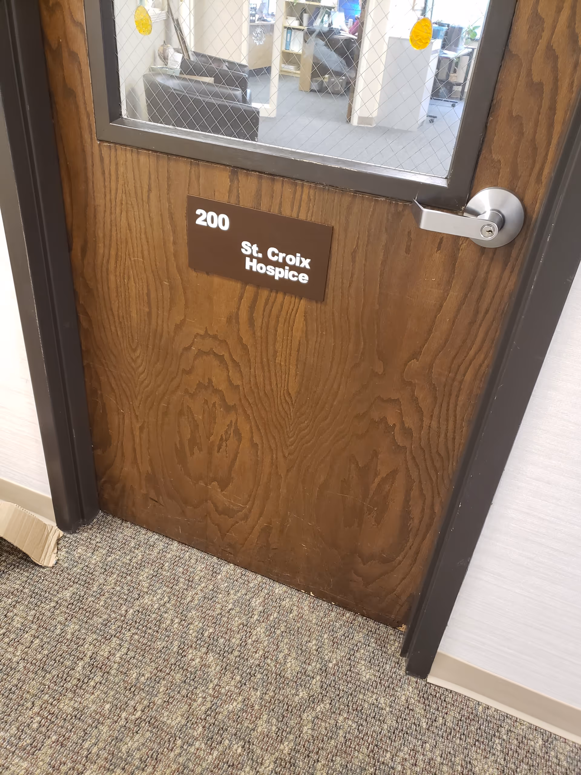Wooden door labeled 200 St. Croix Hospice, with window into a care area.